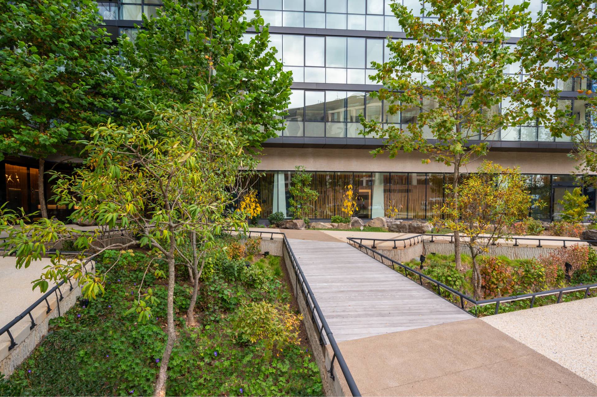 Margarite luxury apartments' courtyard in Washington, DC, with wooden walkway, trees, & plants.